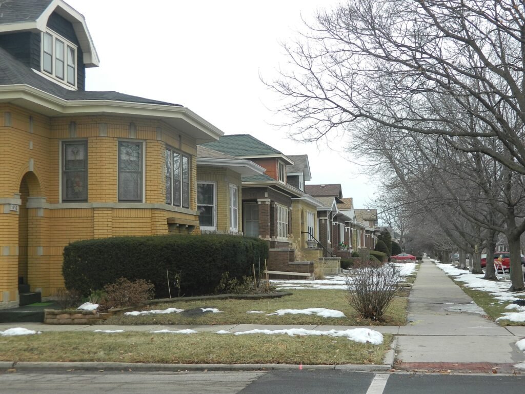 Row of brick Chicago bungalows on a residential street with patches of snow